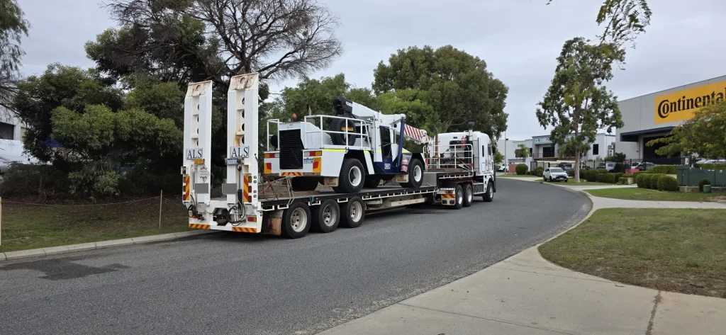 ALS International truck delivering a mobile crane on a float through an urban street