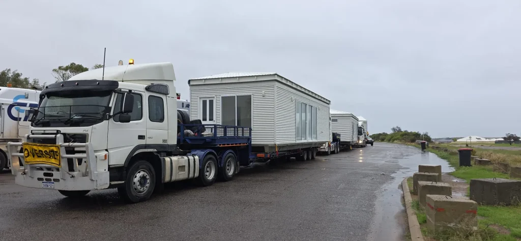 Prime mover hauling a transportable site cabin in wet weather for ALS International